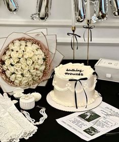 a table topped with a white cake next to a bouquet of flowers and other items