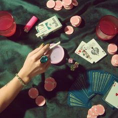 a woman's hand holding a deck of cards next to some pink poker chips