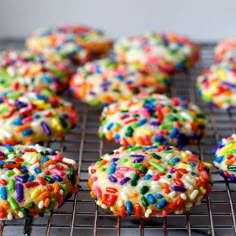 colorful sprinkle covered cookies cooling on a wire rack