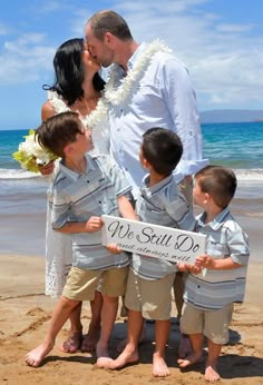 a man and woman kissing their children on the beach