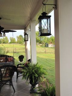 the porch is covered with plants and hanging lantern lights on it's side wall