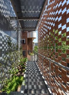 the walkway is lined with brick walls and plants on each side, along with an open area for seating