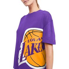 The Tommy Jeans Purple Los Angeles Lakers Bianca T-shirt is a must-have for devoted Los Angeles Lakers fans. With a crew neck and drop shoulders, this comfortable tee boasts screen-printed graphics that proudly showcase your allegiance to the iconic team. Crafted from a cotton and polyester blend, this T-shirt is perfect for game day or any day you want to show your unwavering support for the team. Screen print graphics Drop shoulders Officially licensed Machine wash, tumble dry low Material: 60 Graphic Tee For Sports Events With Crew Neck, College Graphic Tee Tops With Graphic Print, Fan Apparel Tops With Front Print, Relaxed Fit Crew Neck Top For Fan Merchandise, Team Logo Crew Neck Top For Sports Events, Sports Fan Screen Print Tops For Streetwear, Sports Crew Neck T-shirt, Crew Neck Tops With Team Logo For Sports Events, Graphic Tee For Sports Season