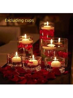 some candles are sitting in glass vases with red roses