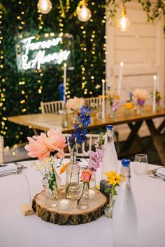 the table is set up with flowers and bottles for guests to sit in front of