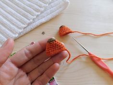 someone is crocheting some tiny carrots on the table