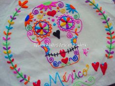 a colorful embroidered sugar skull on a white cloth