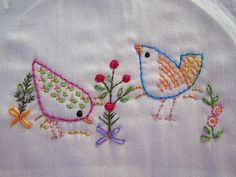 two embroidered birds with flowers on white fabric