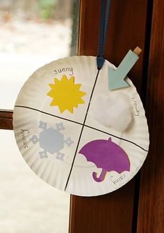 a paper plate hanging on the side of a window sill with an umbrella and sun