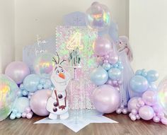 a frozen princess themed birthday party with balloons, streamers and snowman figure on the floor