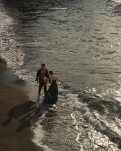 three people are standing in the water at the beach