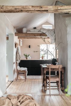 an open kitchen and dining room with wood flooring, white walls and wooden furniture