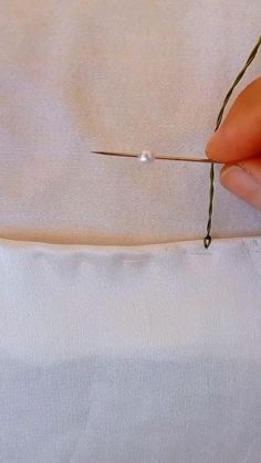 someone is stitching something on the edge of a piece of fabric with a needle