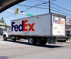 a fed ex truck driving down the street in front of a stoplight and traffic light