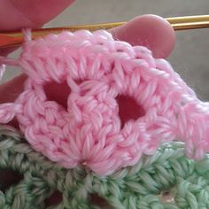 someone crocheting a flower on top of some yarn