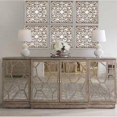 a sideboard with mirrored doors and flowers on top