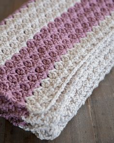 a crocheted blanket laying on top of a wooden floor