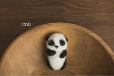 a small stuffed panda bear sitting on top of a wooden bowl