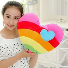 a girl holding a rainbow heart shaped pillow