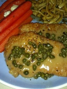 two pieces of chicken with peas and carrots on a plate