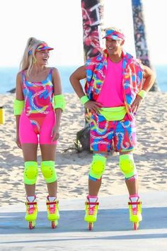 two people wearing roller skates and neon clothing standing on the beach with their arms around each other