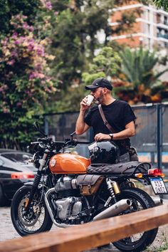 a man sitting on a motorcycle drinking from a cup