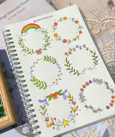 an open notebook with designs on it next to a stamp pad and colored pencils