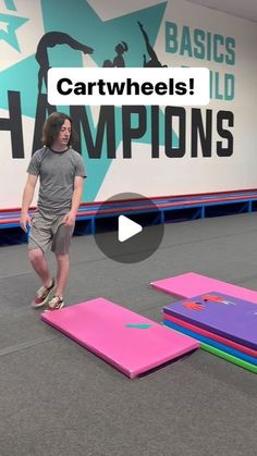 a man standing on top of pink and purple mats in front of a large sign