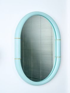 a round blue mirror hanging on the side of a white wall next to a clock