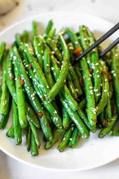 a white plate topped with green beans covered in sesame seeds