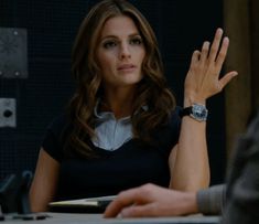 a woman sitting at a table with her hand up