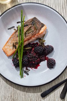 a white plate topped with fish and berries