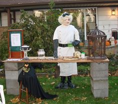 a man dressed as a ghost standing in front of a table with birdcages on it