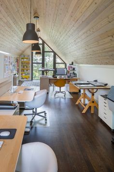 an office with wood floors and white chairs, desks and computer screens on the wall