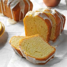 a loaf of lemon pound cake with icing next to it on a white table cloth