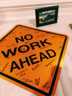 an orange sign sitting on top of a white bed next to a framed photo and other items