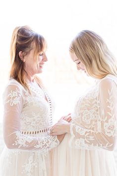 two women standing next to each other in front of a window