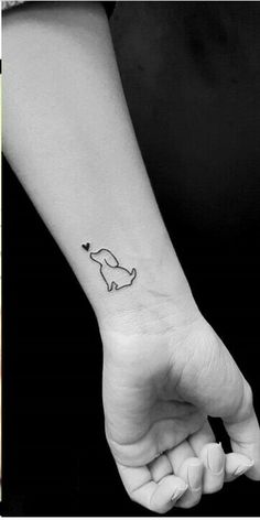 a small dog tattoo on the left inner wrist and an image of a dog with a heart in its mouth