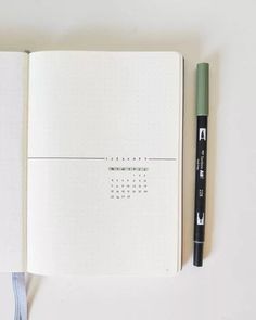 an open notebook with a black marker next to it on top of a white surface