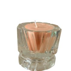 a candle that is inside of a clear glass container on a white surface with a small stick sticking out of it