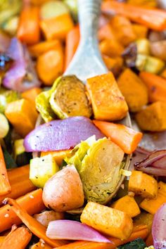 carrots, cabbage and other vegetables are mixed together in a bowl with a spoon