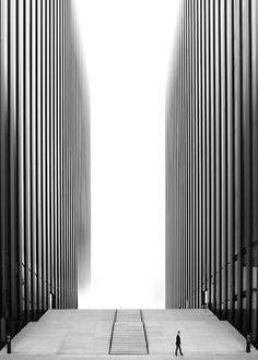 a person walking up some steps in front of tall buildings with columns on each side