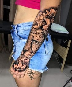 a woman's arm with a lion and flowers on it