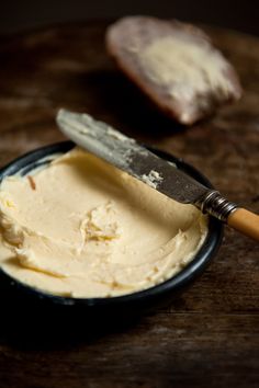 a wooden table topped with a bowl filled with cream