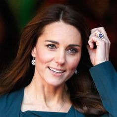 a close up of a person wearing a blue dress and holding a ring on her left hand