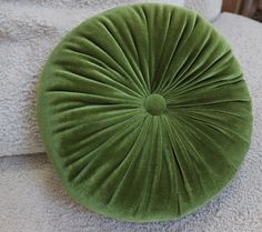 a green round pillow sitting on top of a white couch