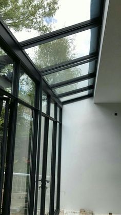 an empty room with glass walls and flooring on the outside, in front of trees