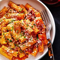 a white plate topped with pasta covered in sauce and parmesan cheese