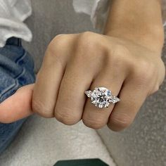 a woman's hand with a three stone ring on her finger, showing the center diamond