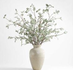 a white vase with some green leaves in it